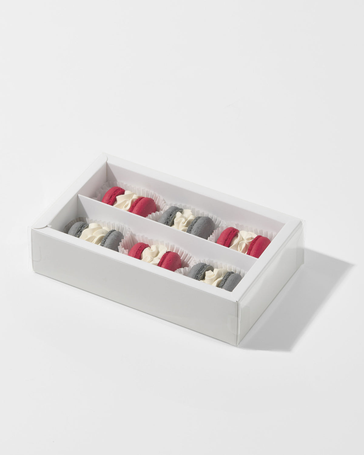 Caja rectangular blanca de pastelería con dos filas de macarons rellenos.
