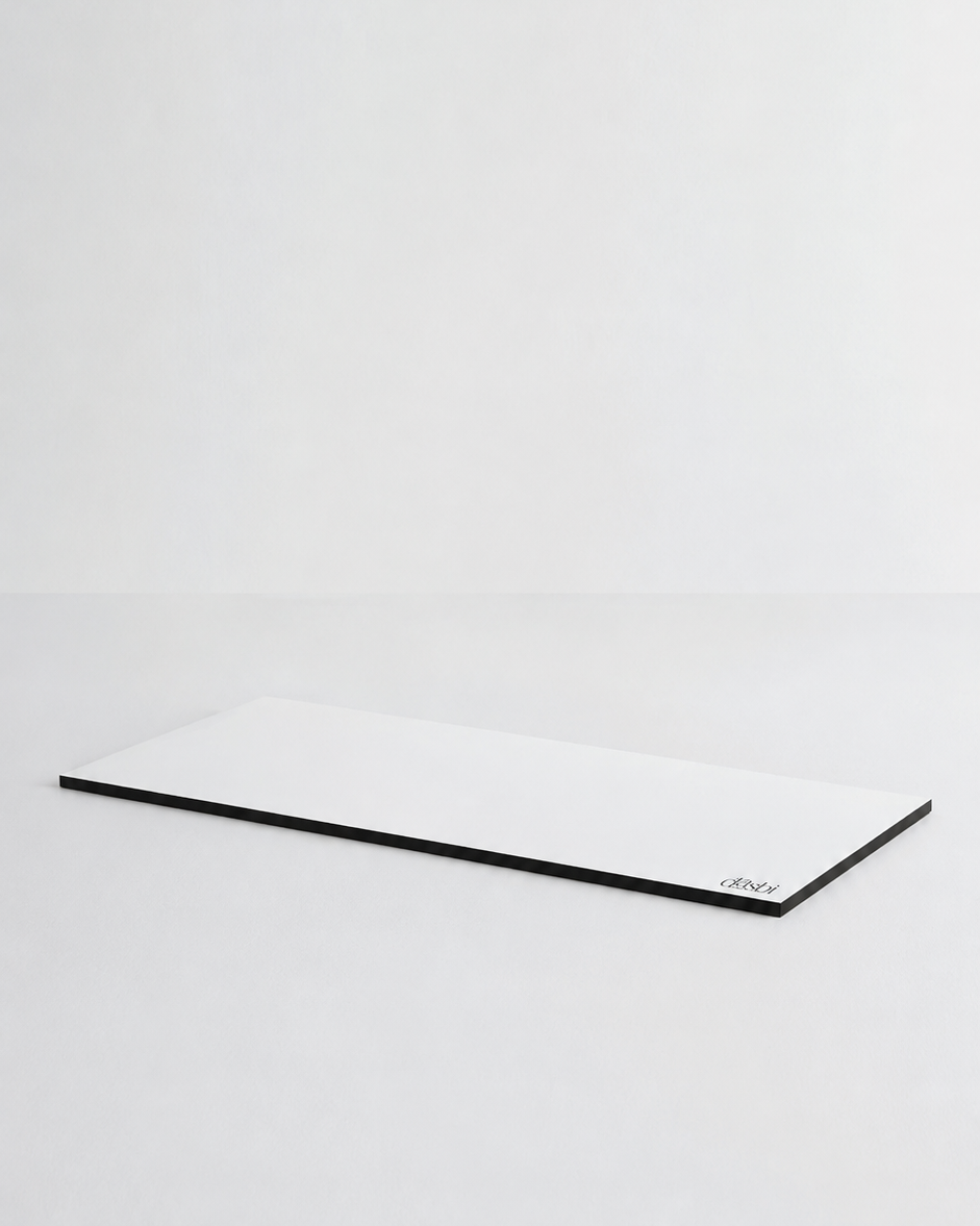 A minimalist white rectangular desk mat with a thin black border, photographed on a seamless light gray studio background.