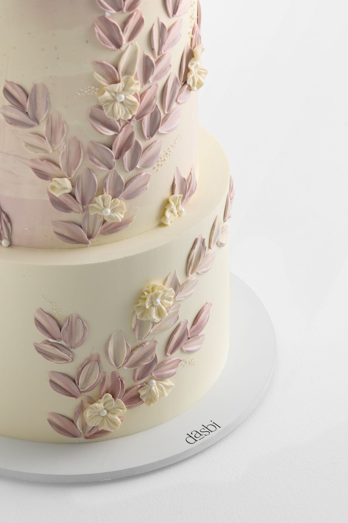 Torta a piani con fiori su un sottotorta rotondo bianco personalizzato con il logo Dasbi.