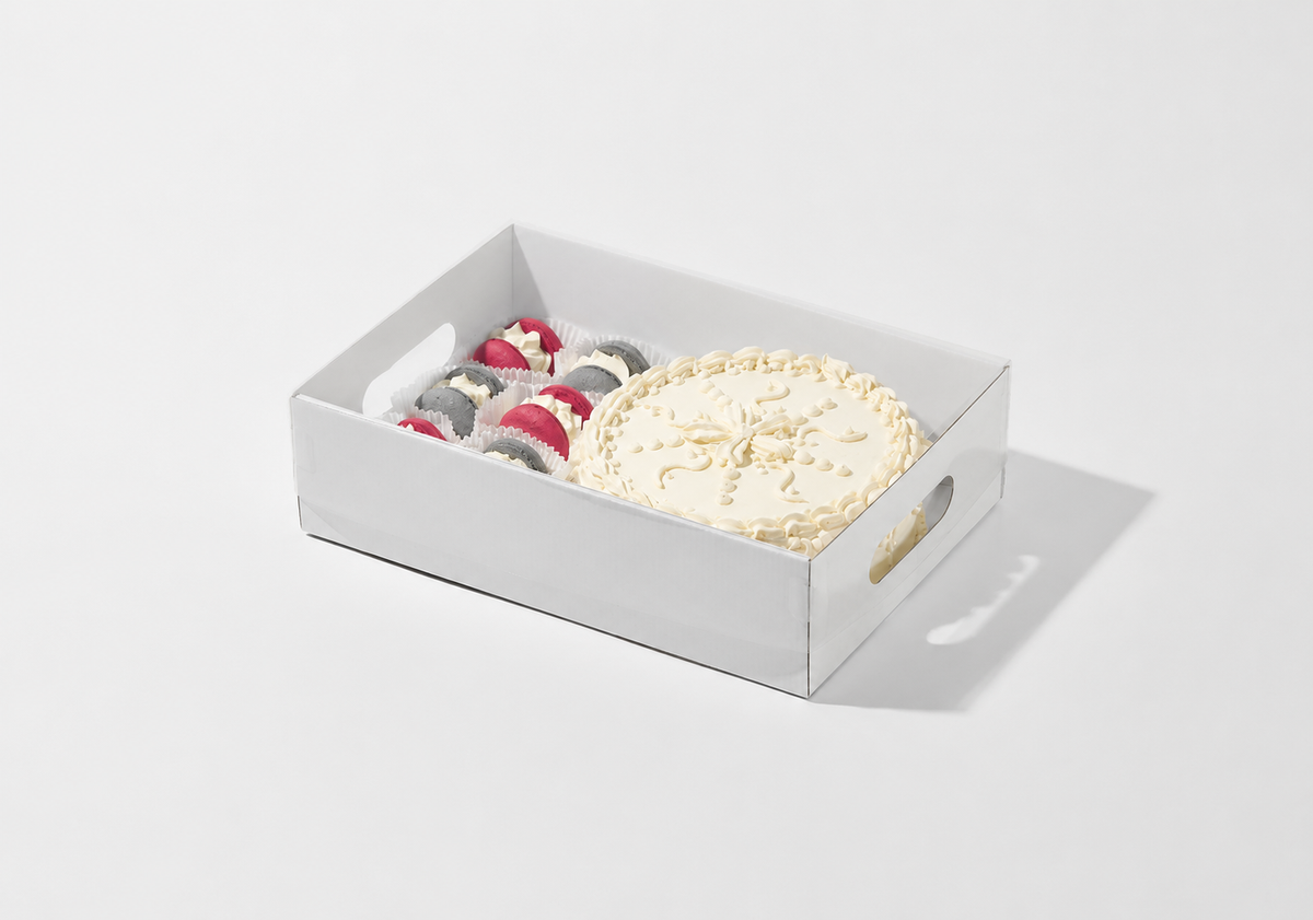 A white rectangular gift box with handles, containing a round cream-colored decorated pastry and several small red-and-white striped pastries, photographed on a clean white background.