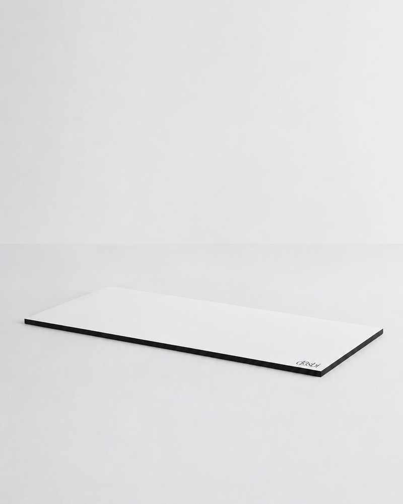 A minimalist white rectangular desk mat with a thin black border, photographed on a seamless light gray studio background.