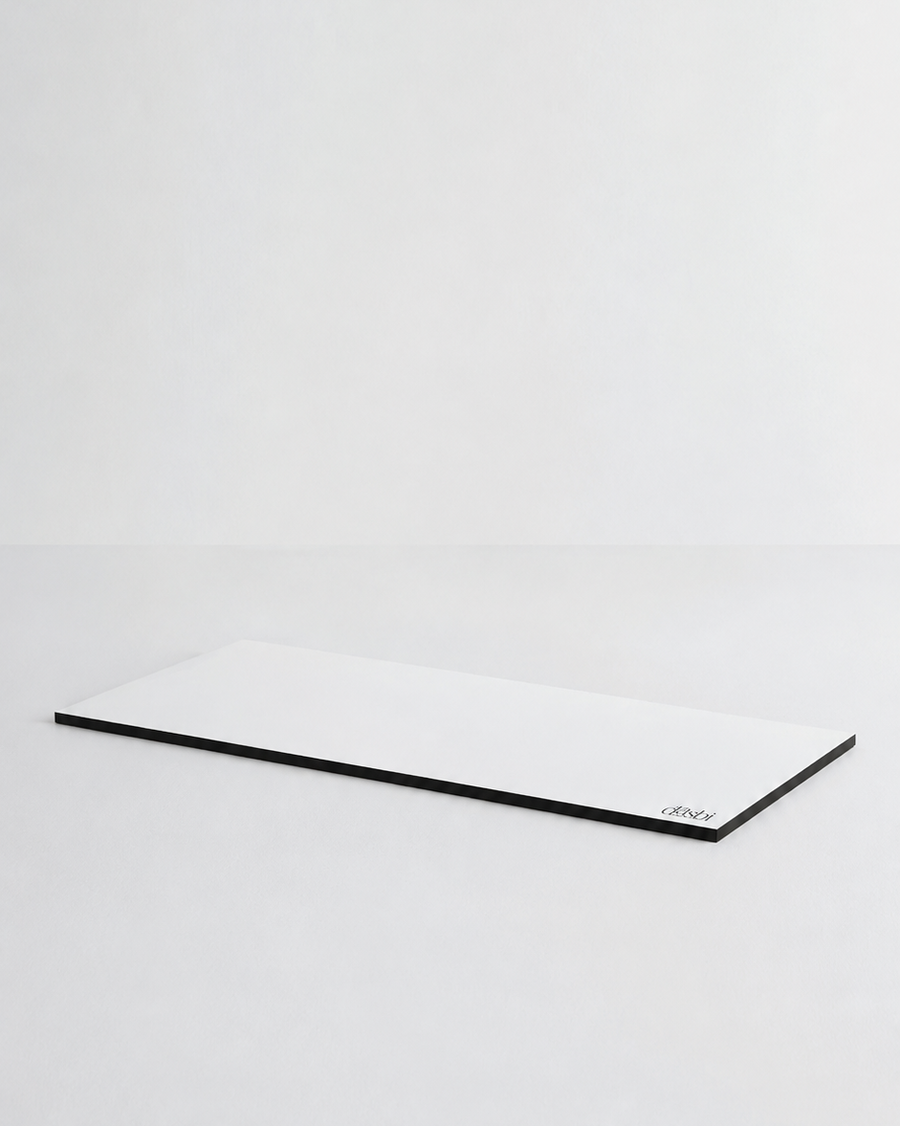 A minimalist white rectangular desk mat with a thin black border, photographed on a seamless light gray studio background.